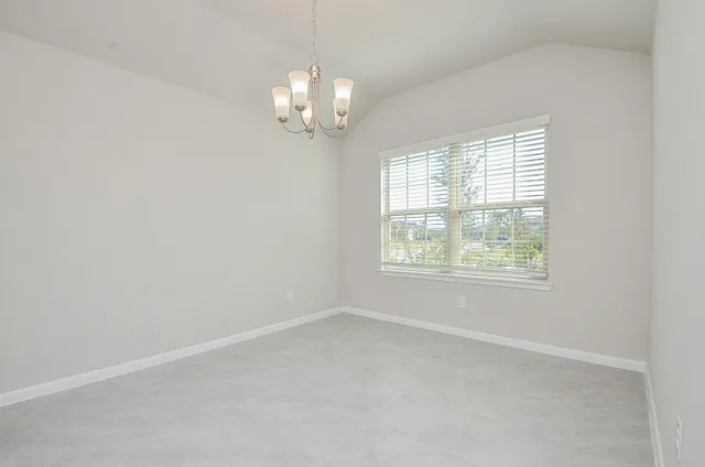 en empty room with windows and chandelier