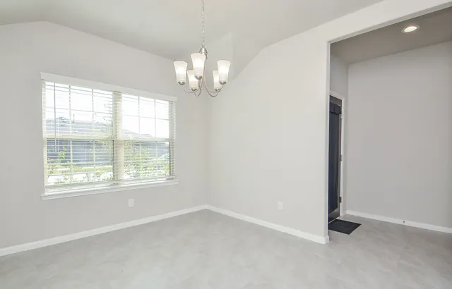 an empty room with chandelier and windows