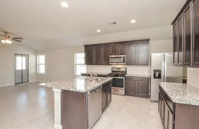 a kitchen with stainless steel appliances granite countertop a refrigerator stove microwave and sink