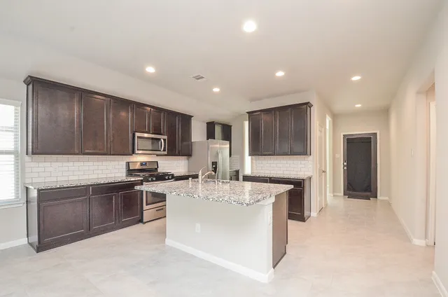 a kitchen with stainless steel appliances granite countertop a stove a sink a refrigerator and a refrigerator