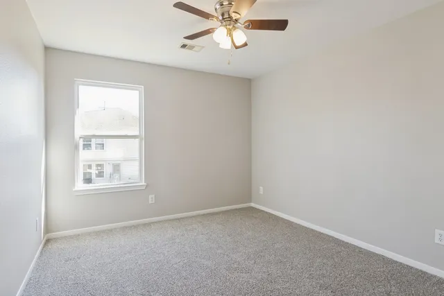 an empty room with a window and a fan