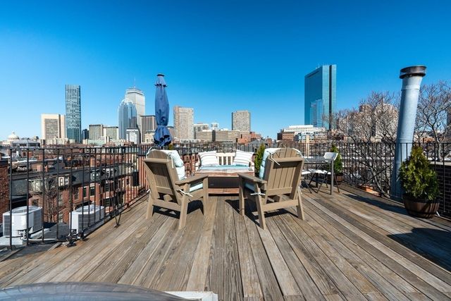a view of a rooftop deck with chairs and wooden floor
