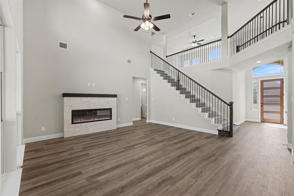 7041 Champion Road Midlothian, TX 76065 - Photo 7 of 30 a view of an empty room with wooden floor a ceiling fan and a fireplace
