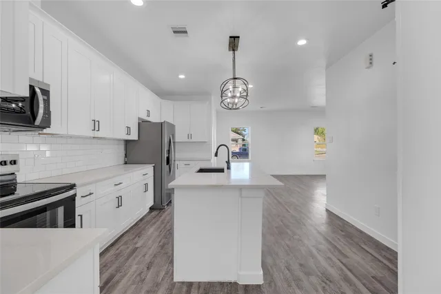 a kitchen with stainless steel appliances granite countertop a sink a stove and a wooden floors