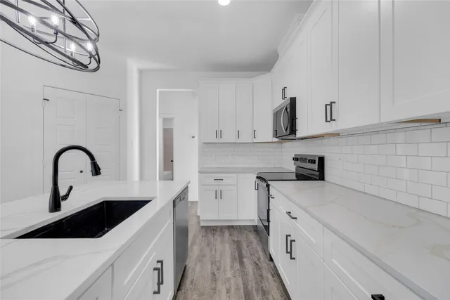 a kitchen with white cabinets a sink and dishwasher