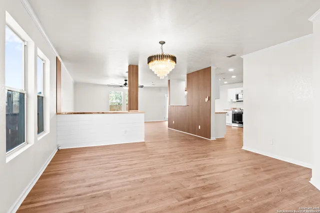 a view of a big room with wooden floor and windows
