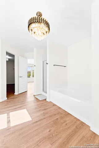 a view of a hallway with wooden floor and a large mirror