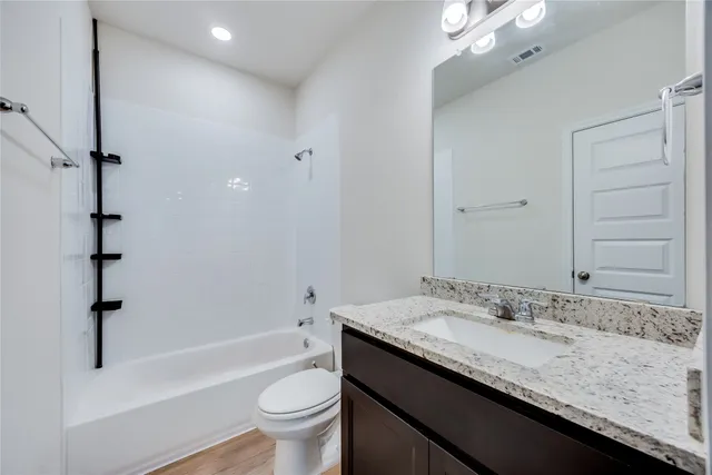 a bathroom with a granite countertop sink a toilet and bathtub