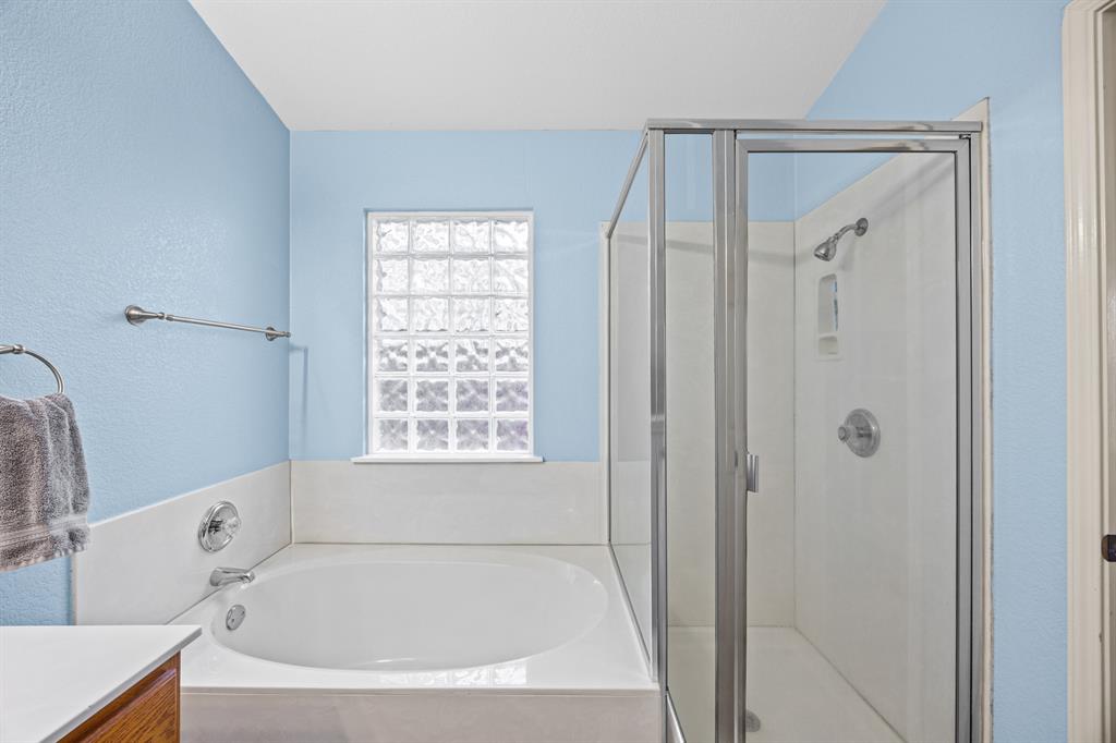 2304 Wilma Rudolph Road Austin, TX 78748 - Photo 11 of 18 Full bathroom with vanity, a stall shower, a bath, and a textured wall