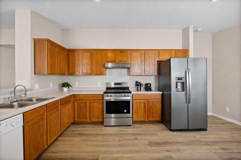 2304 Wilma Rudolph Road Austin, TX 78748 - Photo 6 of 18 Kitchen featuring stainless steel appliances, light countertops, and wood finish cabinets
