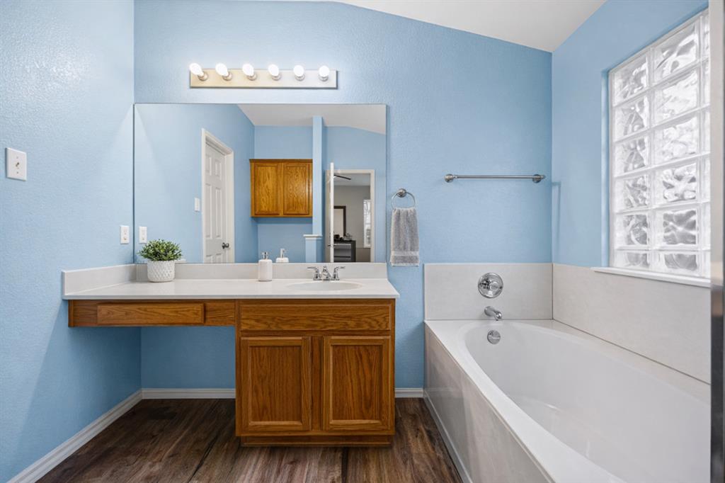 2304 Wilma Rudolph Road Austin, TX 78748 - Photo 10 of 18 Bathroom featuring vanity, a garden tub, dark wood finished floors, and a textured wall