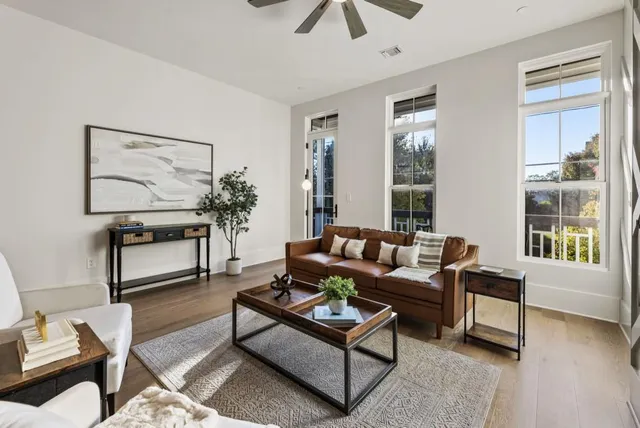 a living room with furniture kitchen view and a wooden floor
