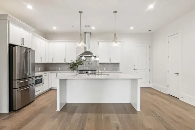 a kitchen with kitchen island a sink a stove a refrigerator and wooden floor
