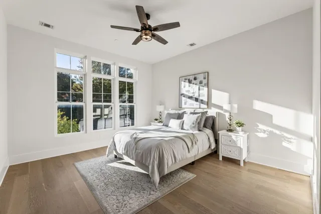 a spacious bedroom with a large bed a chandelier and windows