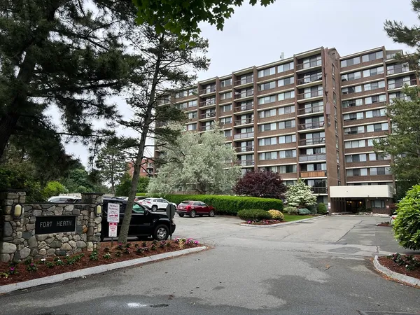a front view of a building with cars parked