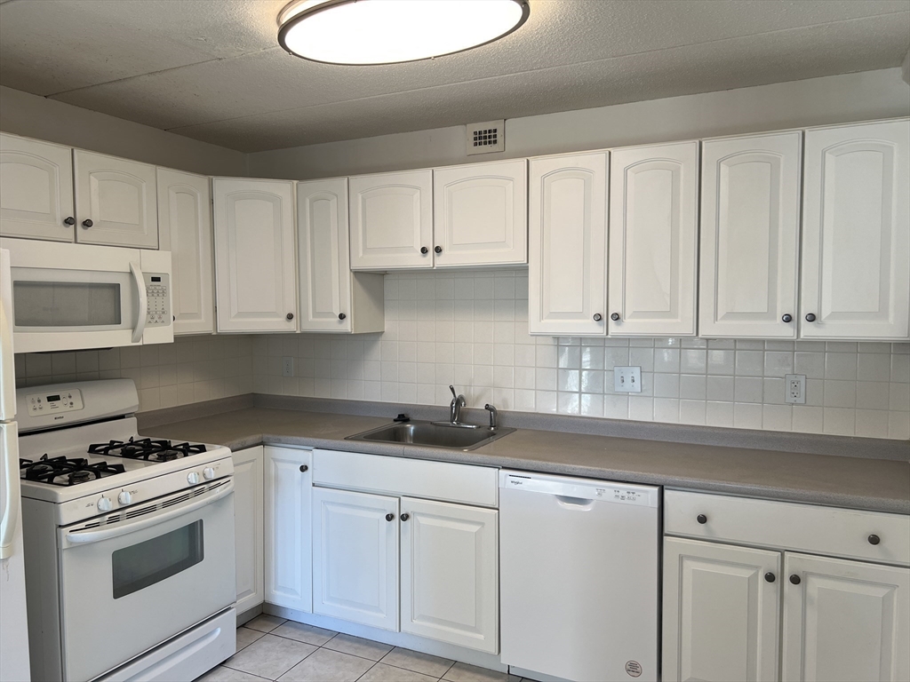 1 Pond Street, Unit 3B Winthrop, MA 02152 - Photo 5 of 11 a kitchen with white cabinets and white appliances