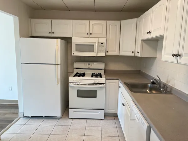 a kitchen with appliances a refrigerator and cabinets