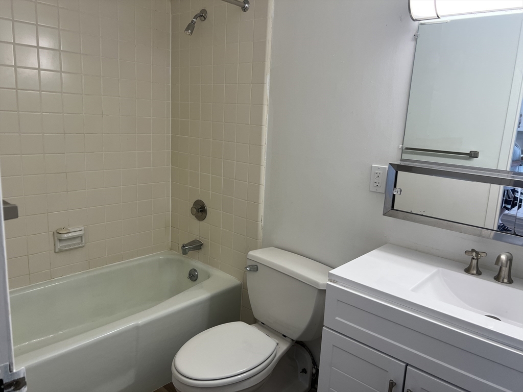 1 Pond Street, Unit 3B Winthrop, MA 02152 - Photo 9 of 11 a white toilet sitting next to a bath tub
