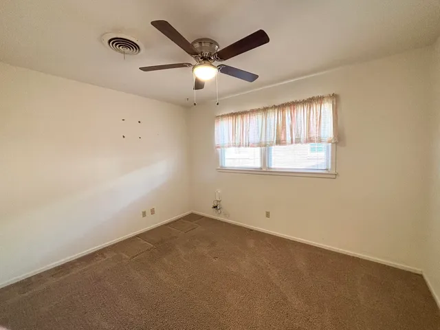 an empty room with a window and a fan
