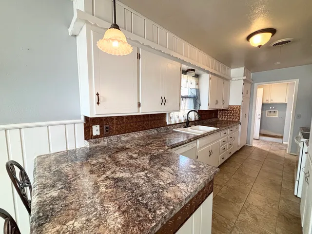 a large kitchen with granite countertop a sink a stove counter space and cabinets
