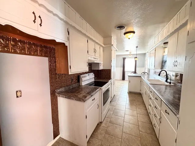 a large white kitchen with a sink and dishwasher a stove with wooden floor