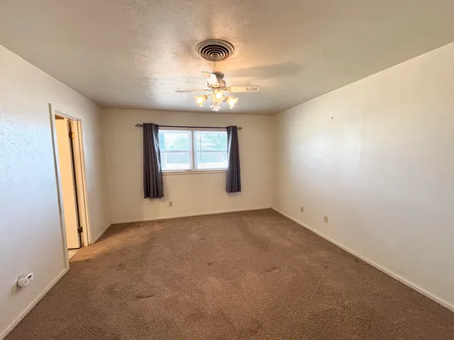 an empty room with a chandelier fan and windows