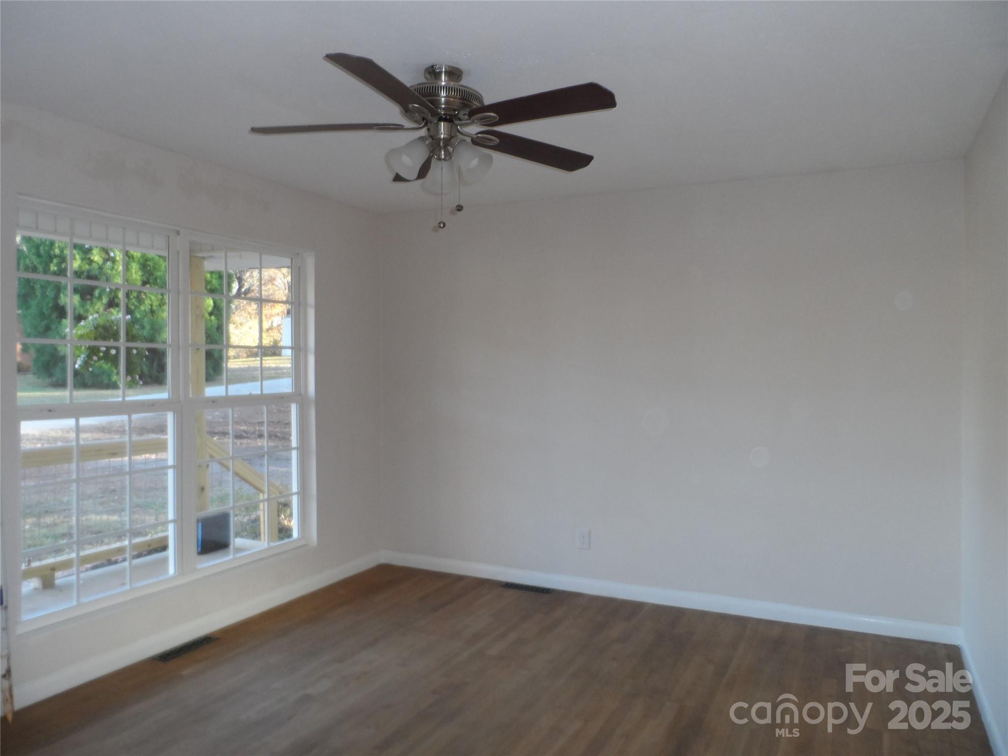 205 Phillips Street Morganton, NC 28655 - Photo 4 of 22 an empty room with wooden floor fan and windows
