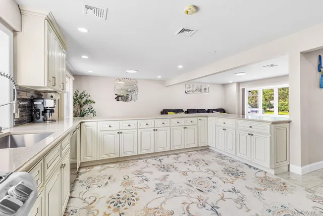 a large white kitchen with stainless steel appliances granite countertop a sink and cabinets