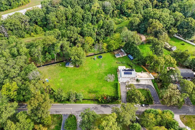 an aerial view of residential house with outdoor space and trees all around
