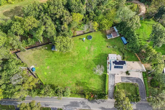 an aerial view of a residential houses with outdoor space and trees all around