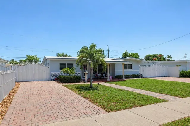 a front view of a house with a yard and potted plants