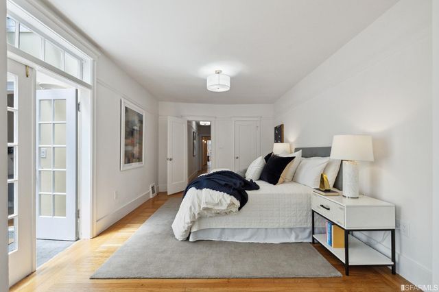 a spacious bedroom with a bed and wooden floor