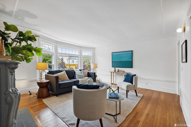 a living room with furniture floor to ceiling window and wooden floor