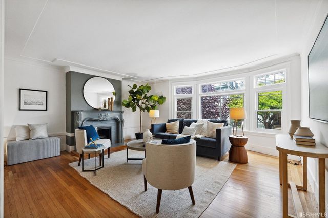 a living room with furniture a fireplace a large window and a potted plant