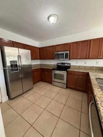 a kitchen with stainless steel appliances granite countertop a refrigerator and a stove top oven