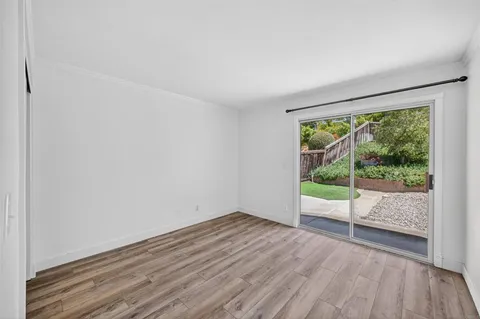 an empty room with wooden floor fan and windows