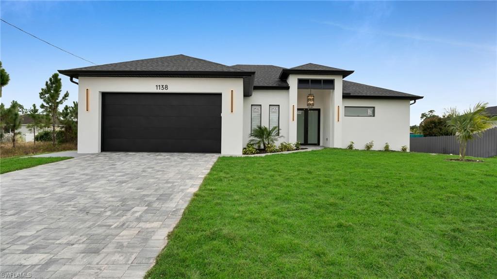 1138 Garibaldi Street East Lehigh Acres, FL 33974 - Photo 1 of 36 Prairie-style home featuring decorative driveway, stucco siding, roof with shingles, and a garage