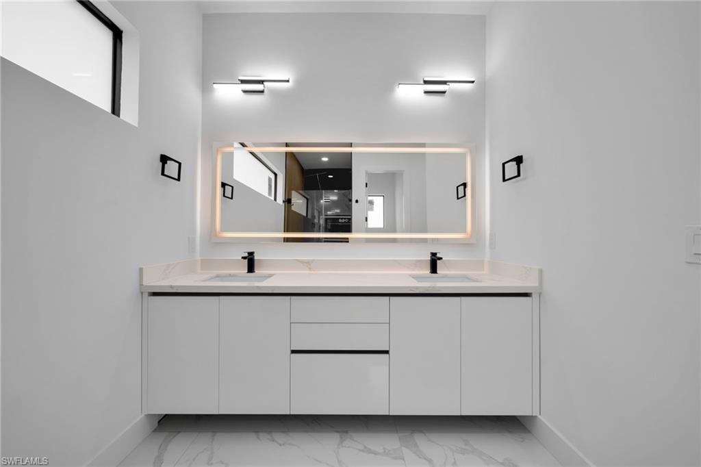 1138 Garibaldi Street East Lehigh Acres, FL 33974 - Photo 15 of 36 Full bath featuring double vanity, light marble finish floors, and a walk in shower