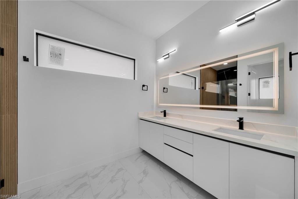 1138 Garibaldi Street East Lehigh Acres, FL 33974 - Photo 16 of 36 Bathroom with double vanity, light marble finish flooring, and a shower stall