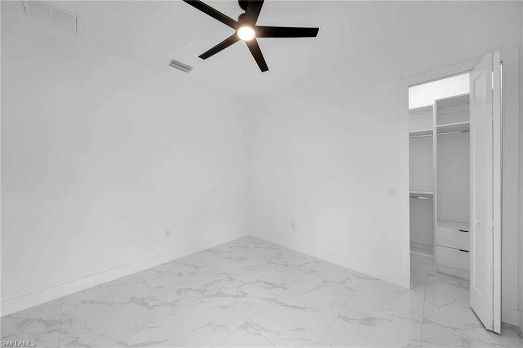 1138 Garibaldi Street East Lehigh Acres, FL 33974 - Photo 21 of 36 Unfurnished bedroom with light marble finish floors, a walk in closet, and a ceiling fan