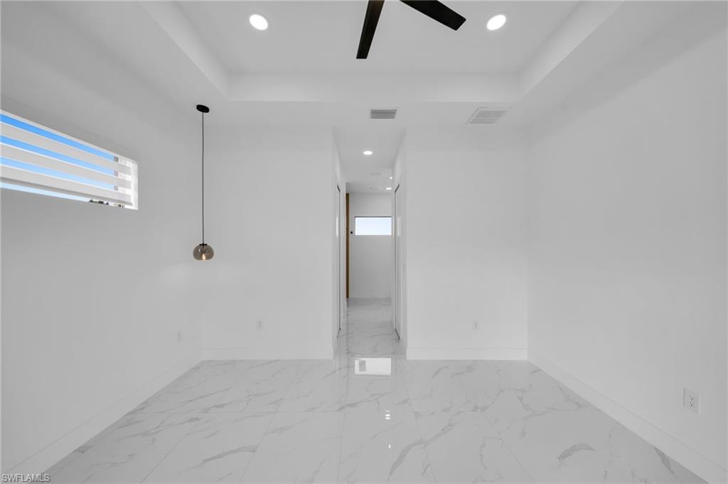 1138 Garibaldi Street East Lehigh Acres, FL 33974 - Photo 28 of 36 Spare room with plenty of natural light, light marble finish flooring, recessed lighting, a ceiling fan, and a raised ceiling