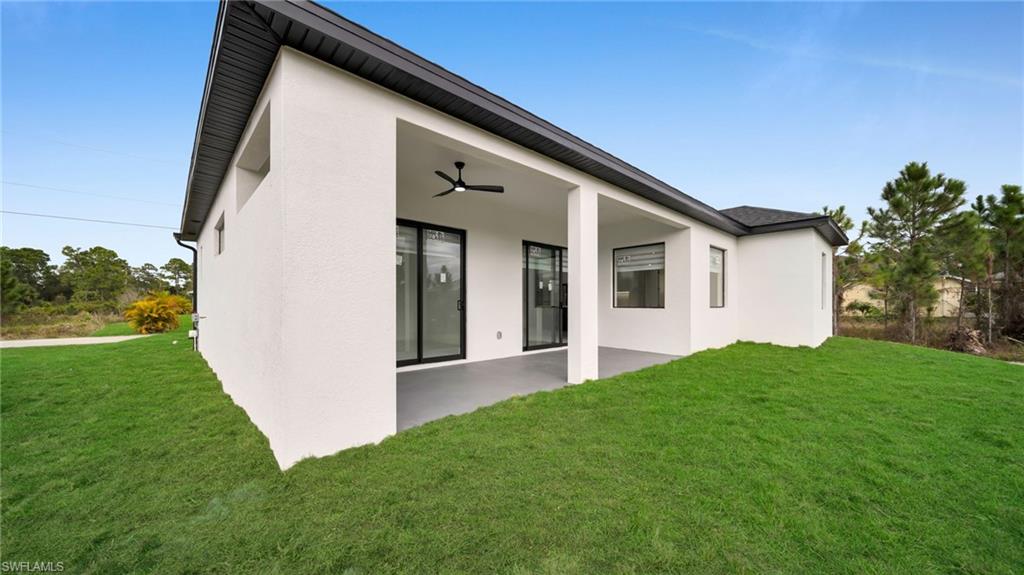 1138 Garibaldi Street East Lehigh Acres, FL 33974 - Photo 35 of 36 Rear view of house featuring a lawn, stucco siding, and a patio area