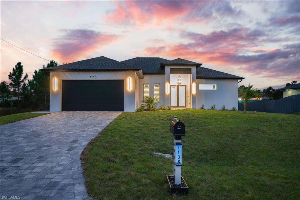 1138 Garibaldi Street East Lehigh Acres, FL 33974 - Photo 4 of 36 Prairie-style house with stucco siding, decorative driveway, and an attached garage