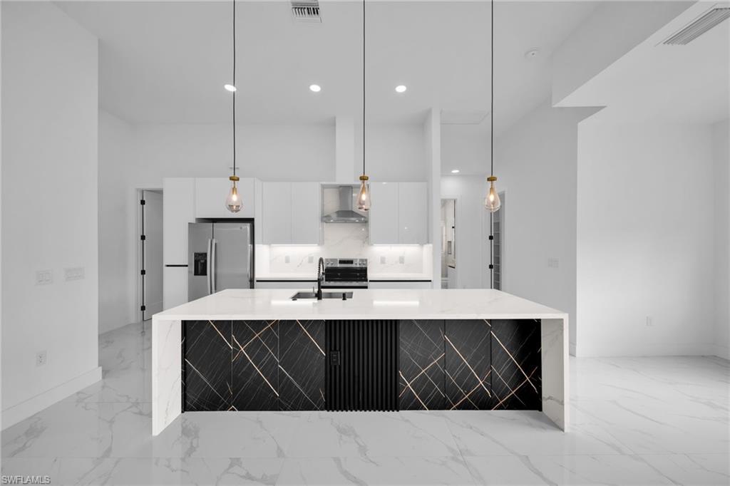 1138 Garibaldi Street East Lehigh Acres, FL 33974 - Photo 10 of 36 Kitchen with appliances with stainless steel finishes, light stone counters, an island with sink, hanging light fixtures, and recessed lighting