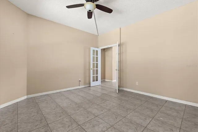 an empty room with a chandelier fan and a window