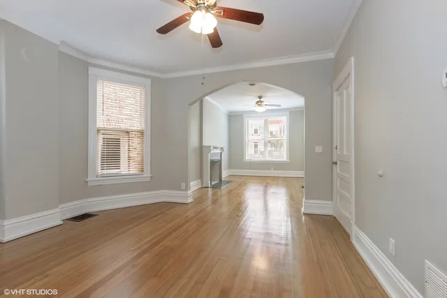 a view of empty room with wooden floor and fan