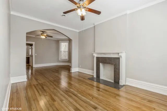 a view of an empty room with wooden floor and a fireplace