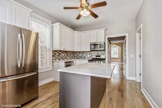 a kitchen with kitchen island a counter top space wooden floor and stainless steel appliances