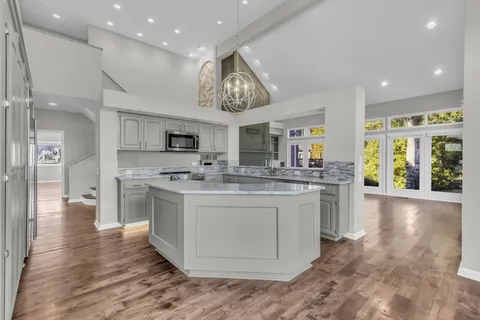 a large kitchen with stainless steel appliances kitchen island granite countertop a sink and cabinets