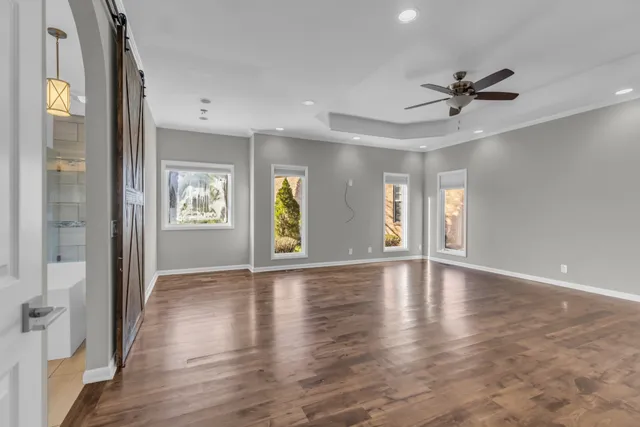 a view of an empty room with a window and wooden floor